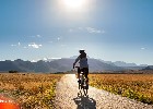 Firefly Radfahrer, der der Sonne entgegenfährt. Berge im Hintergrund. Prärie im Vordergrund. 81049